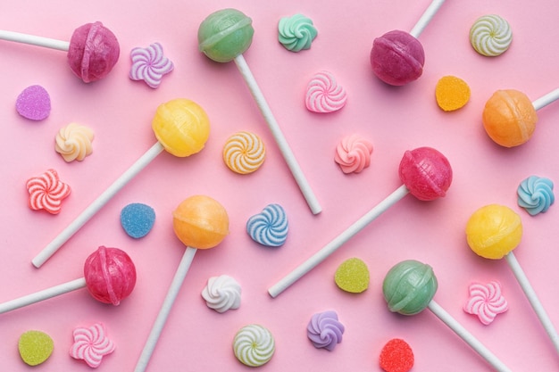 Sweet lollipops and candies on pink background