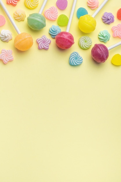 Sweet lollipops and candies on yellow background