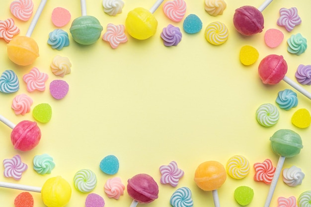 Sweet lollipops and candies on yellow background