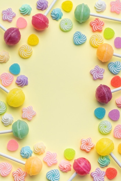 Sweet lollipops and candies on yellow background