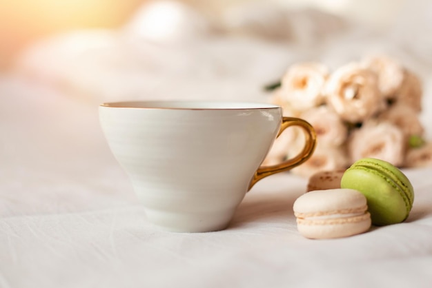 Sweet macaroons, mug and white roses