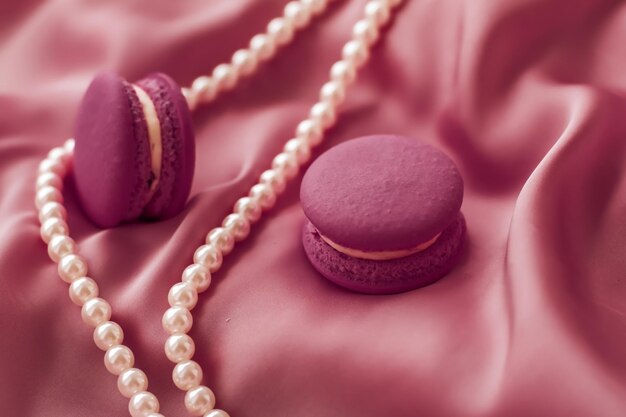 Sweet macaroons and pearls jewellery on silk background parisian chic jewelry French dessert food and cake macaron for luxury confectionery brand holiday gift