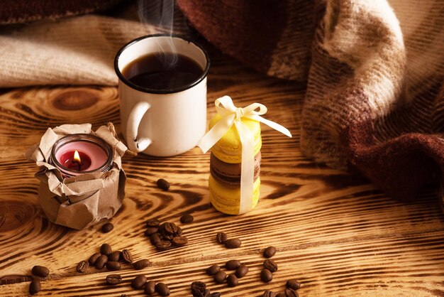 Sweet macaroons on wooden board with cup of coffee and a burning candle Atmospheric photo Content for social networks