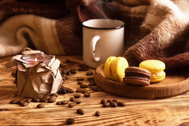 Sweet macaroons on wooden board with cup of coffee and a burning candle Atmospheric photo Content for social networks