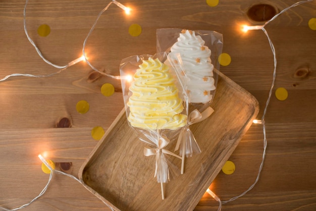 Sweet meringue in hand, on a stick in the form of a Christmas tree