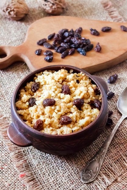 Sweet millet porridge with dark raisins in ceramic rustic bowl