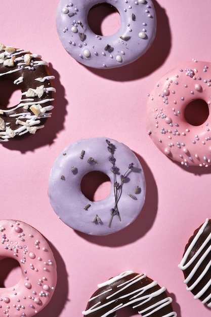 Sweet multicolored donuts on purple with lavender flowers.