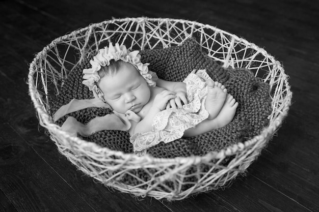 Sweet newborn baby girl sleeps in the basket Dark brown background