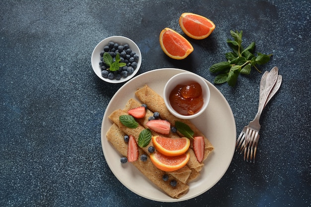 Sweet pancakes wrapped with fresh mint strawberries blueberries oranges and jam