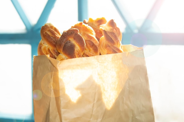 Sweet pastries in a paper bag in front of a window with bright sunlight and glare