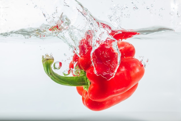 Sweet pepper in water splashes, red sweet pepper on white