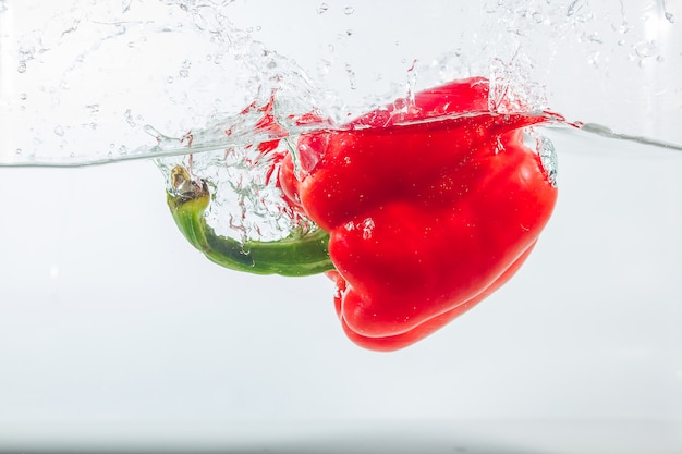 Sweet pepper in water splashes, red sweet pepper on white