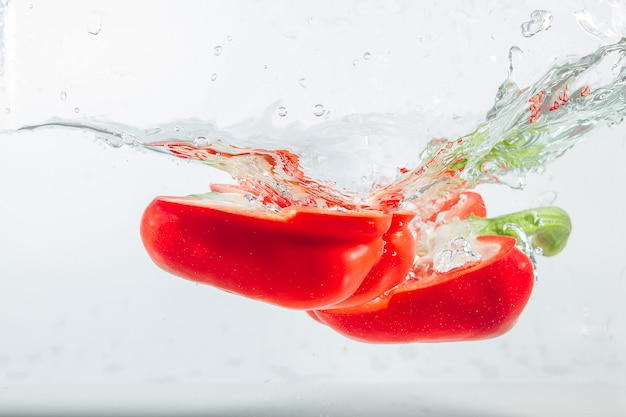 Sweet pepper in water splashes, red sweet pepper on white