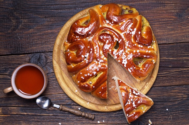 Sweet pie with jam and cup of tea on wooden table, top view