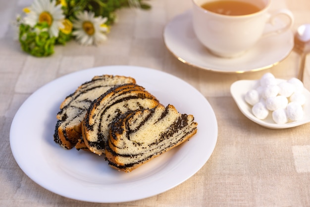 Sweet poppy seed cake on a plate, on a table, and a Cup of tea