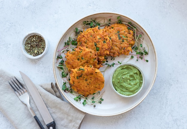 Sweet potato fritters with creamy avocado dip on ceramic plate