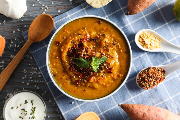 Sweet potato puree in bowl spoon and ingredients on wooden background top view