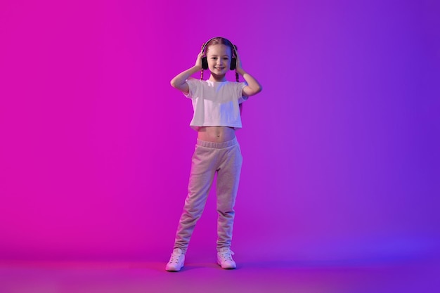 Sweet preteen child girl in summer outfit using wireless headphones