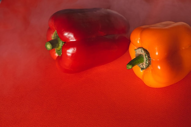 SWEET RED AND ORANGE PEPPERS ON A RED BACKGROUND