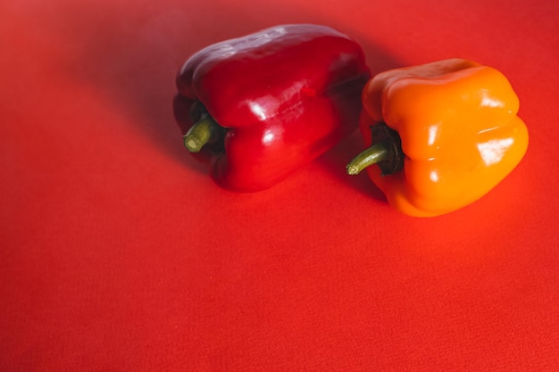 SWEET RED AND ORANGE PEPPERS ON A RED BACKGROUND