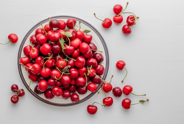 Sweet ripe cherries on plate placed on white table