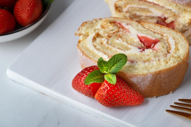 Sweet roll stuffed with strawberry and cream decorated with strawberries powdered sugar