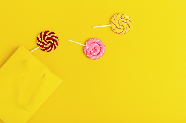 Sweet round candy lollypops with stripes on stick out of yellow paper package. Creative concept escape to freedom for Birthday, party, holidays.