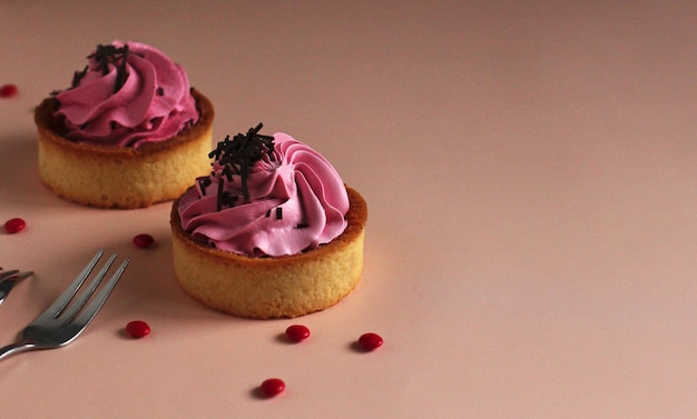 Sweet round tartlet with pink cream and chocolate on a pink background