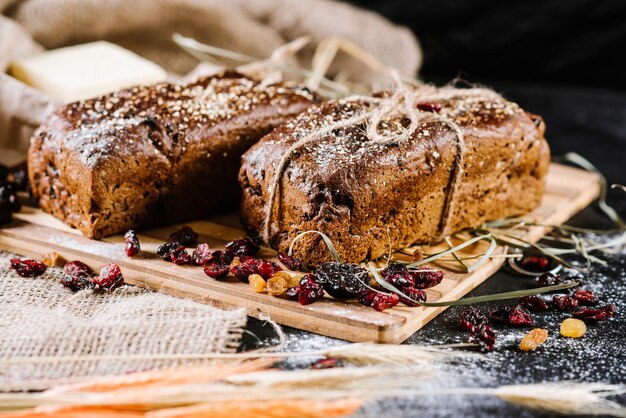 Sweet rye bread and wheat on black wooden background