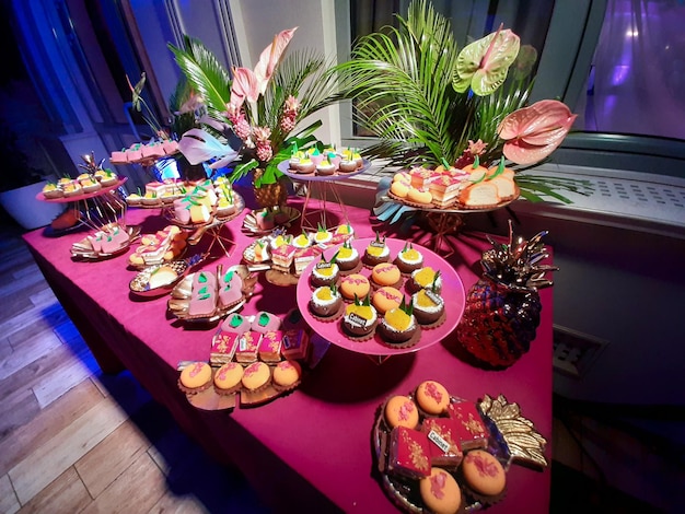 Sweet table with cakes at the banquet decorated with plants The red dress is lined