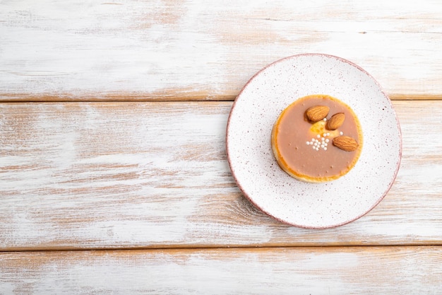 Sweet tartlets with almonds and caramel cream  on a white wooden background. top view, flat lay, copy space.