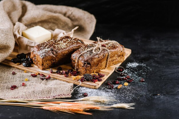 Sweet and tasty bread and wheat on black wooden background