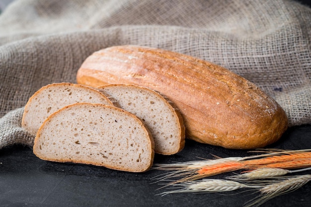 Sweet tasty bread and wheat on wooden background