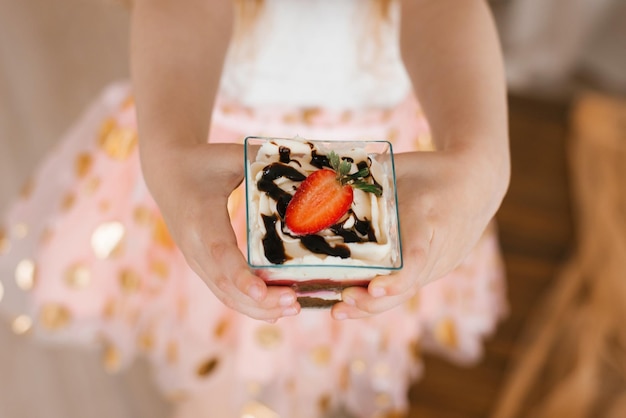 Sweet trifle dessert in the hands of a little girl on a holiday