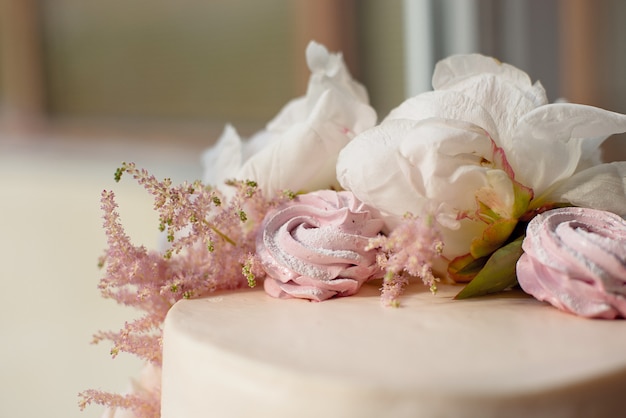 Sweet white cream cake round with pink roses flowers and white peony on top