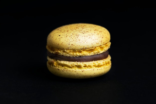 Sweet yellow macaroon isolated on black background