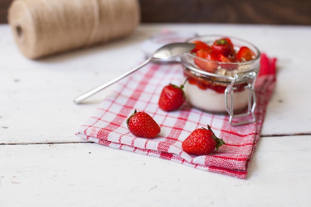 Sweet yogurt with fresh delicious strawberries and oat flakes. Spool of thread on the background