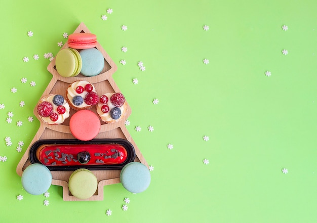 Sweets macaroons and cakes in plate in a shape of Christmas tree