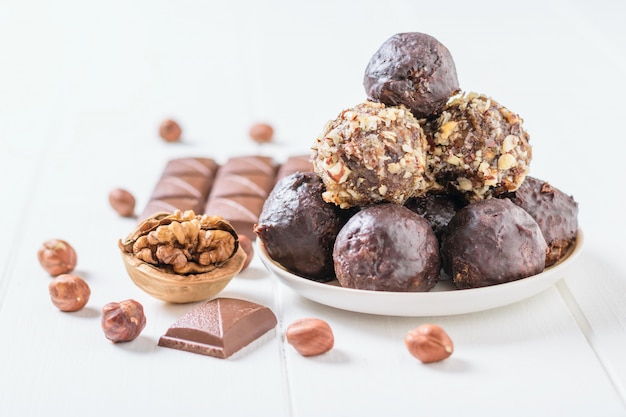 Sweets made at home from nuts, dried fruits and chocolate on a white wooden table.