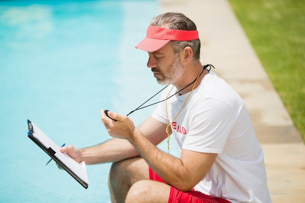 Swim coach looking at stopwatch near poolside