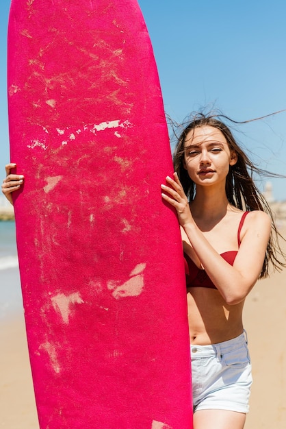 The swimmer holds his hands on a standing surfboard and stares into the distance the wind blows her hair