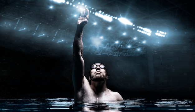 Swimmer in the pool raises his hands up.