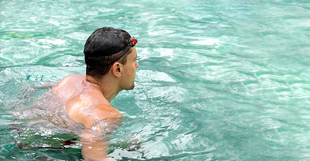 Swimmer young athletic brunette man wearing swimming goggles in pool panorama banner healthy lifesty