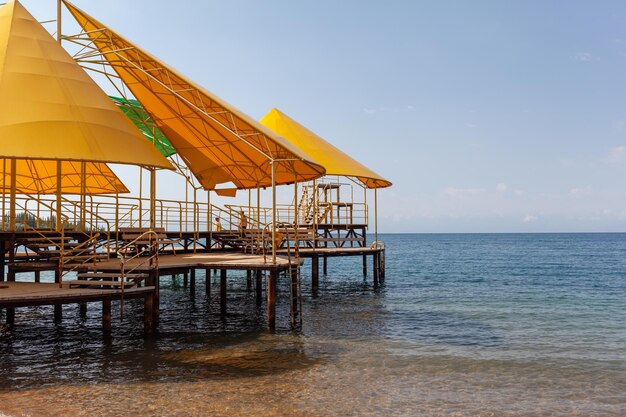 Swimming area or pier on the sea. A large pier with a roof wooden planks and rusty stairs descending