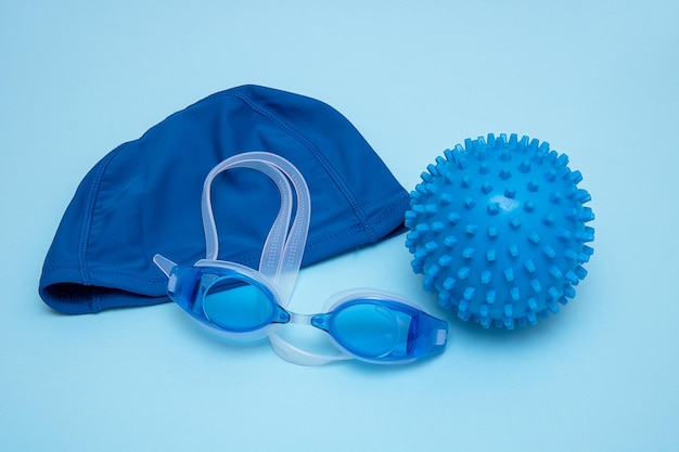 Swimming cap goggles and ball for playing in the water on a blue background