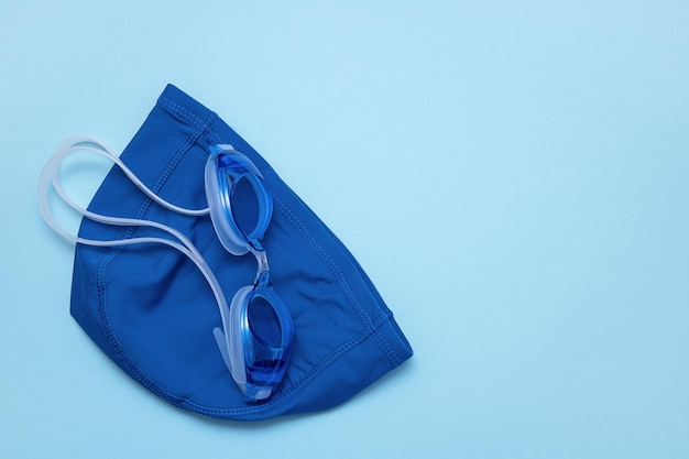 Swimming cap and goggles on a blue background with copy space