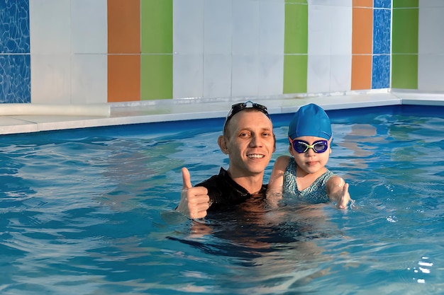 Photo swimming class in the pool, the coach and the little girl in the water show the class