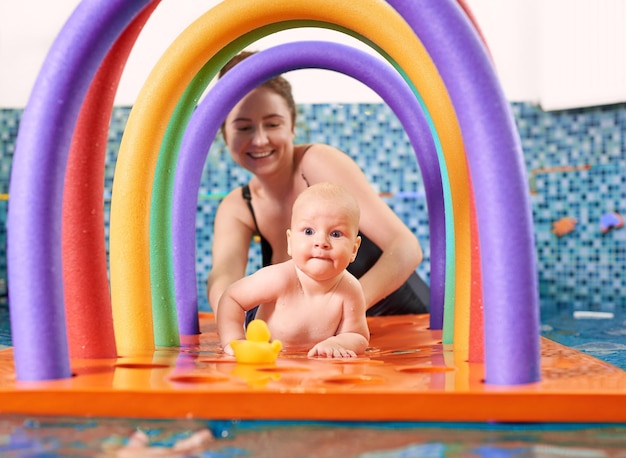 Swimming classes for little ones infant with mother in swimming pool during training