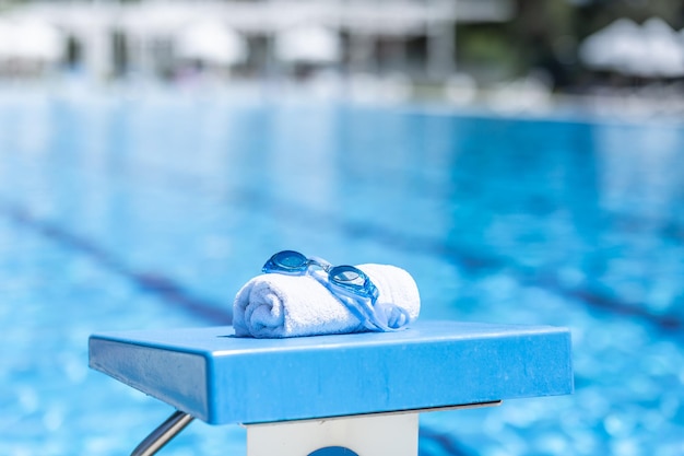 Swimming goggles and a towel placed on the starting bridge by the swimming pool