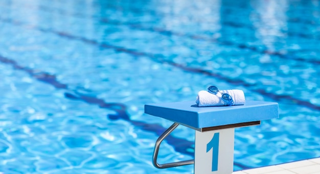 Swimming goggles and a towel placed on the starting bridge by the swimming pool